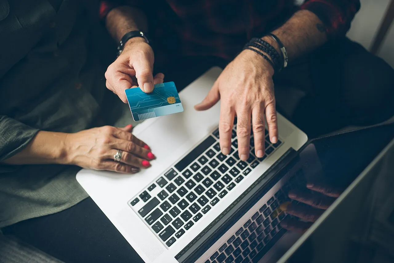 Manos sobre un portátil revisando información con una tarjeta