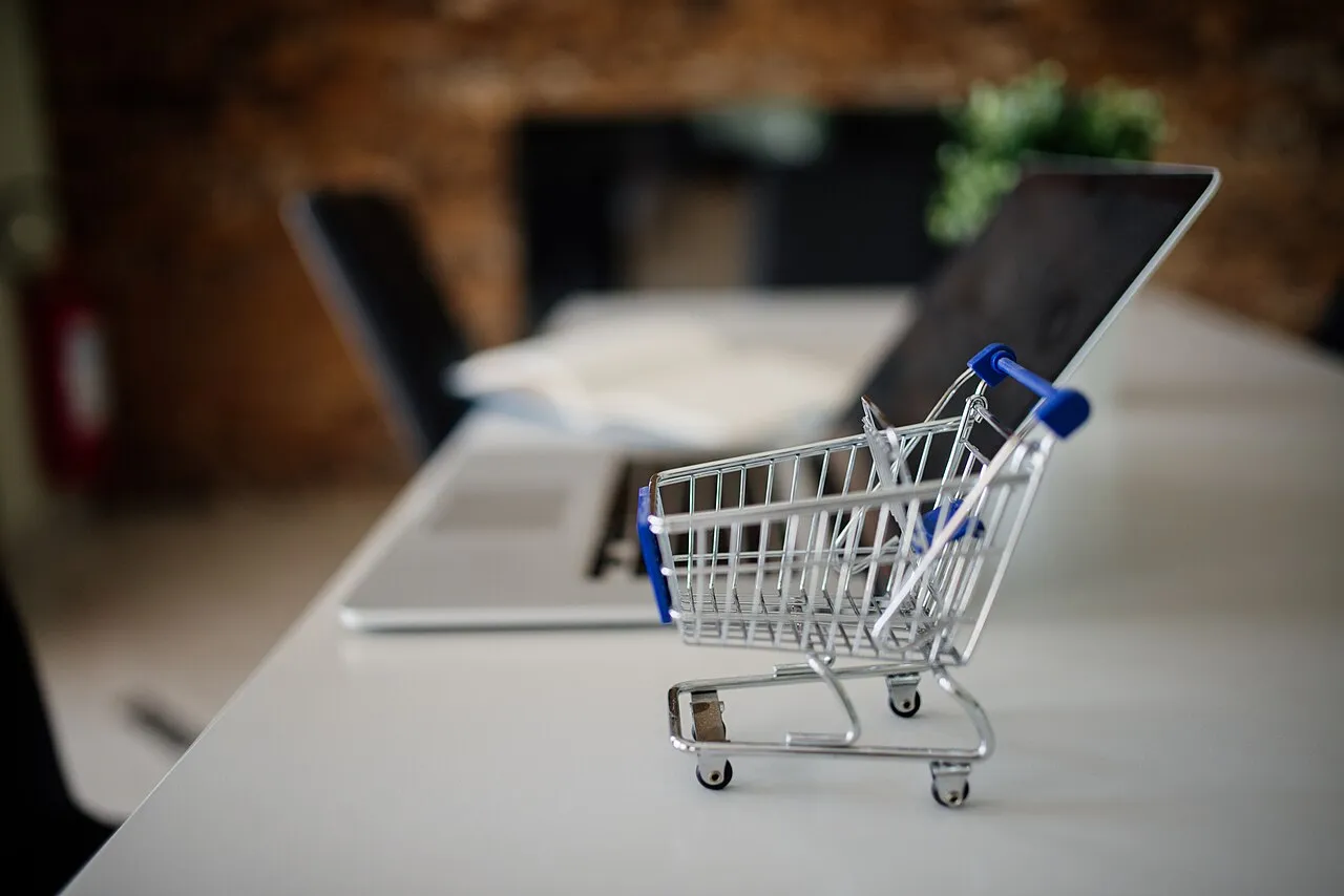 Carrito de compras en miniatura junto a un portátil